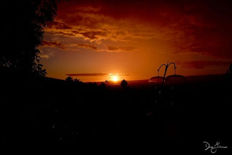 A sunset over the southern california coast with puffy clouds overhead.